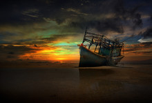 Old Abandoned Boat On The Shore Under Twilight Which Illuminates Him Hull And A Dramatic Cloudy Sky