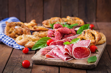 Pretzels and various sausages on wooden background. Oktoberfest.