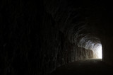 Dark road in a natural rocky tunnel and the light of the exit