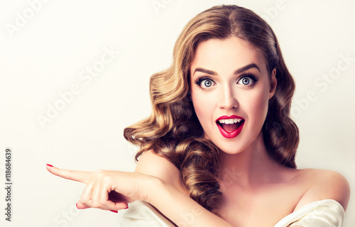 Plakat Kobiety niespodzianka pokazuje produkt Piękna dziewczyna z kędzierzawym włosy wskazuje strona. Prezentujesz swój produkt. Wyraziste mimikę twarzy