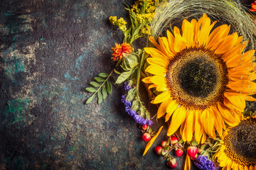 Sunflowers with berries and flowers. Floral autumn decoration on dark rustic vintage background, top view, border