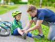 © Ermolaev Alexandr - father putting band-aid on young boy's injury who fell off his bike