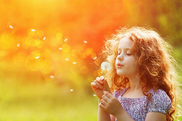 Wall Mural - Beautiful child enjoy blowing dandelion in spring park.