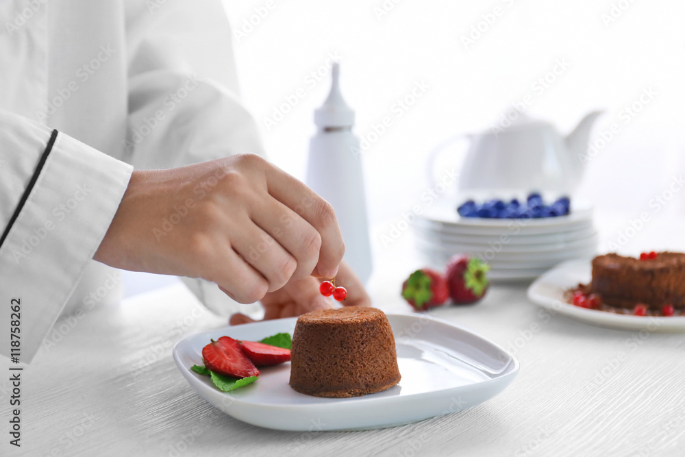 Chef decorating chocolate fondant with red currant, closeup