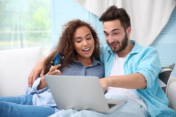 Poster - Young man and woman using credit card and laptop for online shopping