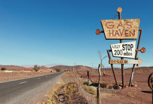 Deserted Road  And Tall Vintage Gas Sign  In Typical Moroccan Landscape Near Ouarzazate,  Morocco.
