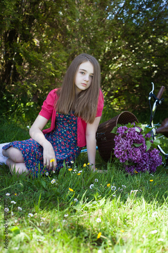 Beautiful teenage girl sitting in a field with a bicycle laying on the ...