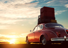 Retro Red Car With Luggage On Roof Rack At Sunset. Travel, Vacation Concepts.