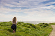 young girl with long blonde hair happily running along a coastal path on a beautiful sunny day.