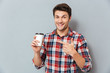 © Drobot Dean - Young handsome smiling man pointing finger at takeaway coffee cup