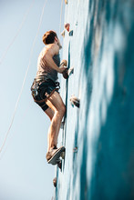 Young Man Doing Exercise In Mountain Climbing On Practice Wall