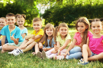 Wall Mural - Happy kids sitting on grass in park