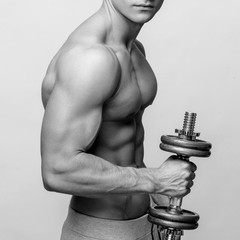 Shirtless bodybuilder holding dumbell and showing his muscular arms.