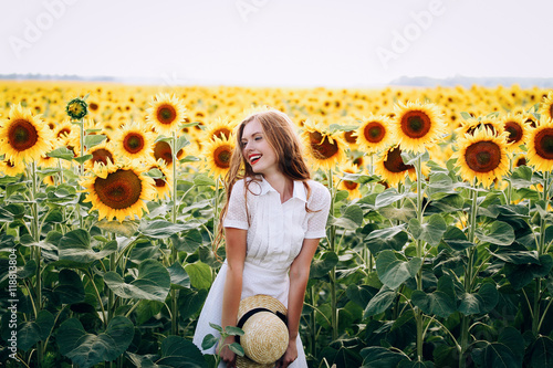 Photographie Belle douce fille sexy dans une robe blanche marchant sur un champ de tournesols