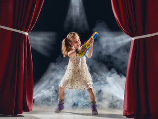 girl playing guitar on stage