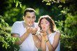 © barbiturat - Portrait of a beautiful young couple blowing dandelion flower