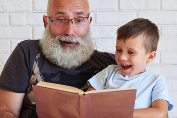 Wall Mural - Grandfather and his grandson spending time together reading a fu