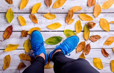 Wall Mural - legs of runner. blue sports shoes. colorful autumn leaves.