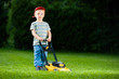 © KopoPhoto - Cute boy mows lawn by yellow lawn mower