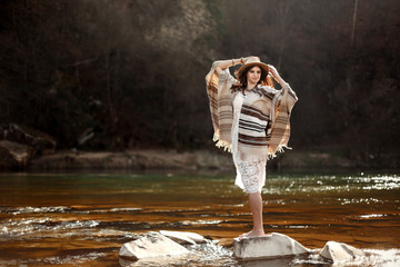 Canvas Print - beautiful woman traveler standing on rocks in river and playing