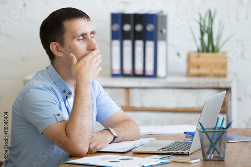 Portrait Of Young Man Sitting At The Table In Front Of Laptop