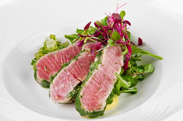 Tuna in herbs with ginger melon on a plate on a white background, closeup