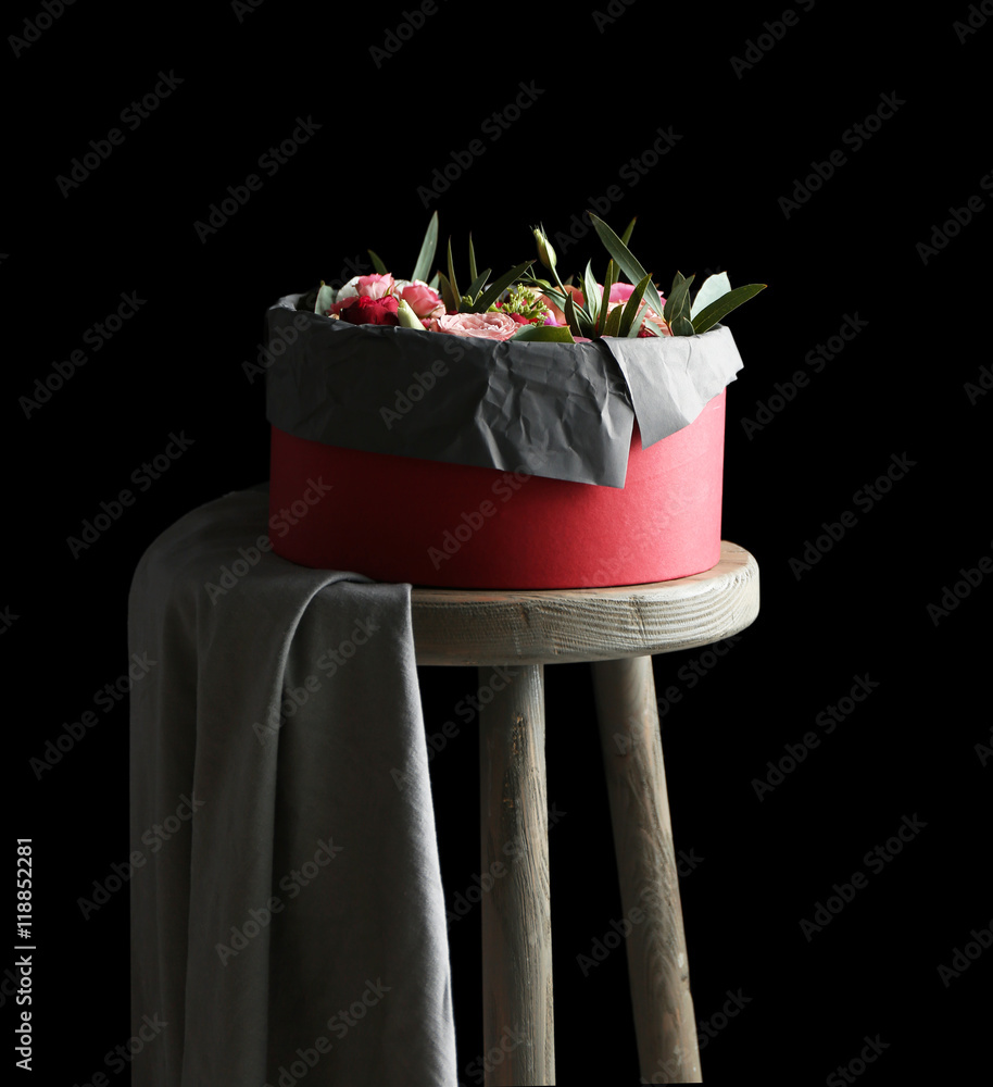 Box with fresh flowers and macaroons on the chair, black background