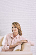 © DragonImages - Elegant mature woman sitting on sofa at home