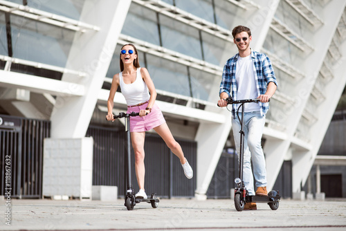 Fotografía Joyful friends riding a kick scooter.