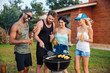 © Drobot Dean - Smiling people drinking beer and cooking on barbeque grill outdoors