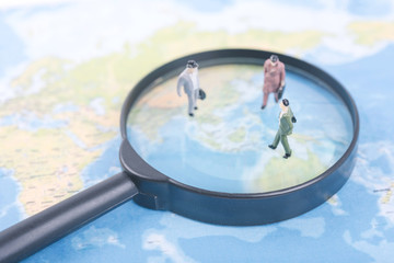 Miniature business people on magnifier and world map. business international travel concept