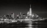 Fototapeta Nowy Jork - Skyscrapers of New York City Financial District illuminated at night. Aerial panoramic view of Lower Manhattan and the Hudson River in Black & White