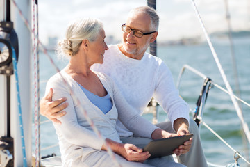 Wall Mural - senior couple with tablet pc on sail boat or yacht