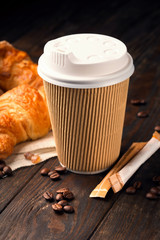 Wall Mural - Coffee to go in a paper cup with croissants on wooden table, selective focus