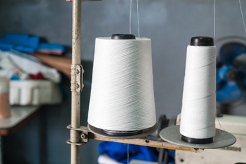 Bobbin of white thread on sewing machine in the factory