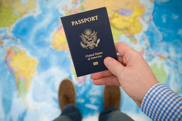 Man's hand holding US passport. Map background. Ready for traveling. Open world.