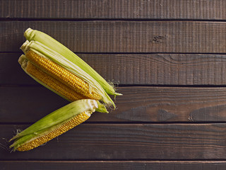 Fresh sweet corn cobs on wooden table. Top view. Free copy space..