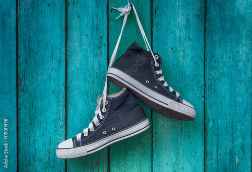 Fotografía pair of blue men's sports sneakers hanging from a nail on the wa