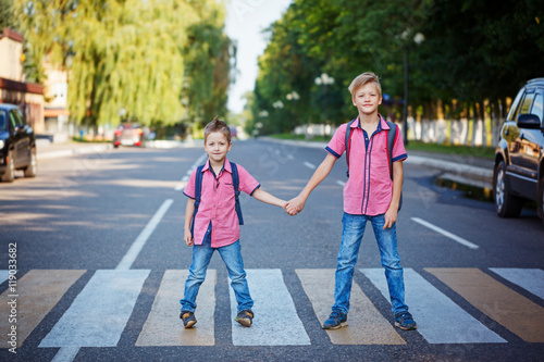 Kids with backpack walking, holding on warm day on the road . плакат