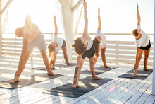 Group Of People Practicing Yoga On The Seaside During The Sunrise