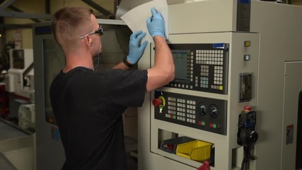 engineer programming a cnc machine and reading technical drawing