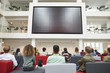 © Monkey Business - Students watching big screen in university atrium, back view