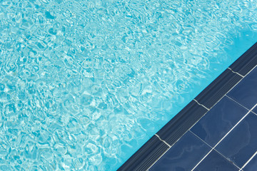 swimming pool water wave with sun reflections.