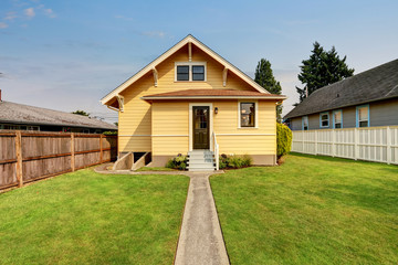 Backyard view of yellow siding craftsman house.