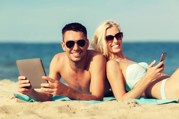 Wall Mural - happy couple with tablet pc sunbathing on beach