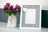 Fototapeta  - Photo frame stands on a shelf next to the flowers