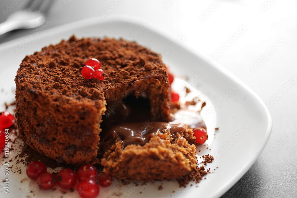 Tasty chocolate fondant with red currant on white plate, closeup