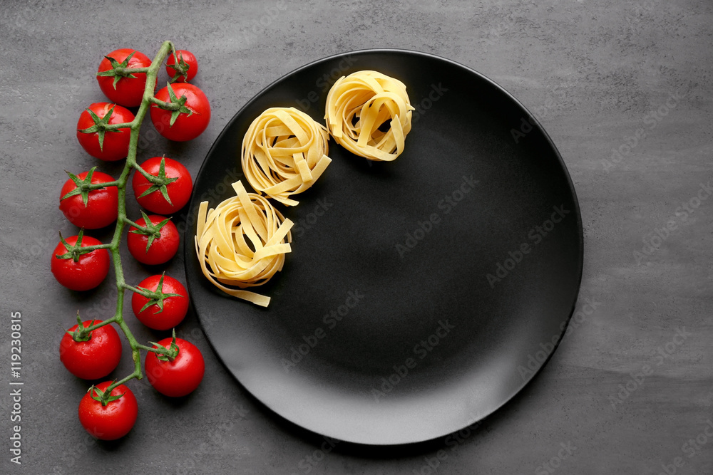 Cherry tomatoes and pasta with black plate on table