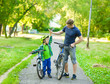© Ermolaev Alexandr - father and son give high five while cycling in the park