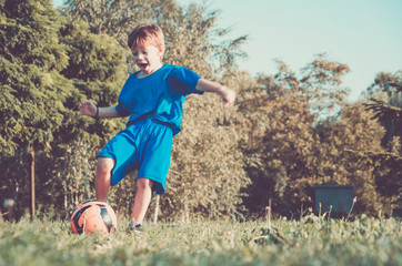 small boy football player running and hits the ball